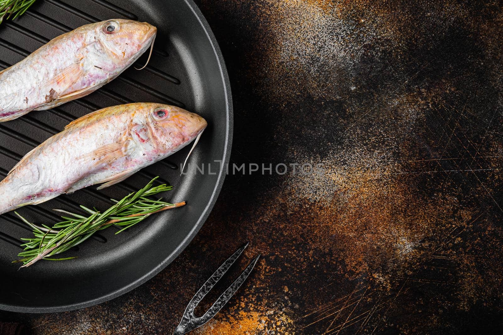 Raw Goatfish fresh whole fish, with ingredients and herbs on cast iron frying pan skillet, on old dark rustic table background, top view flat lay, with copy space for text by Ilianesolenyi
