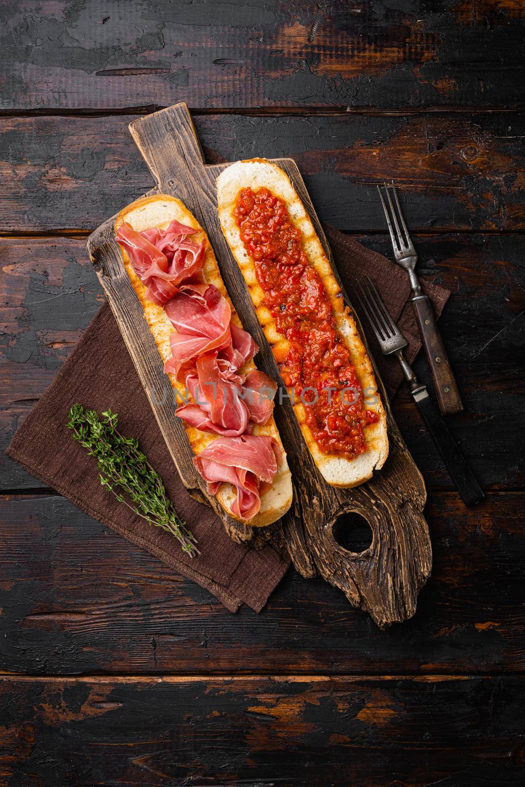 Crusty toast with fresh tomatoes and cured ham, on old dark wooden table background, top view flat lay, with copy space for text