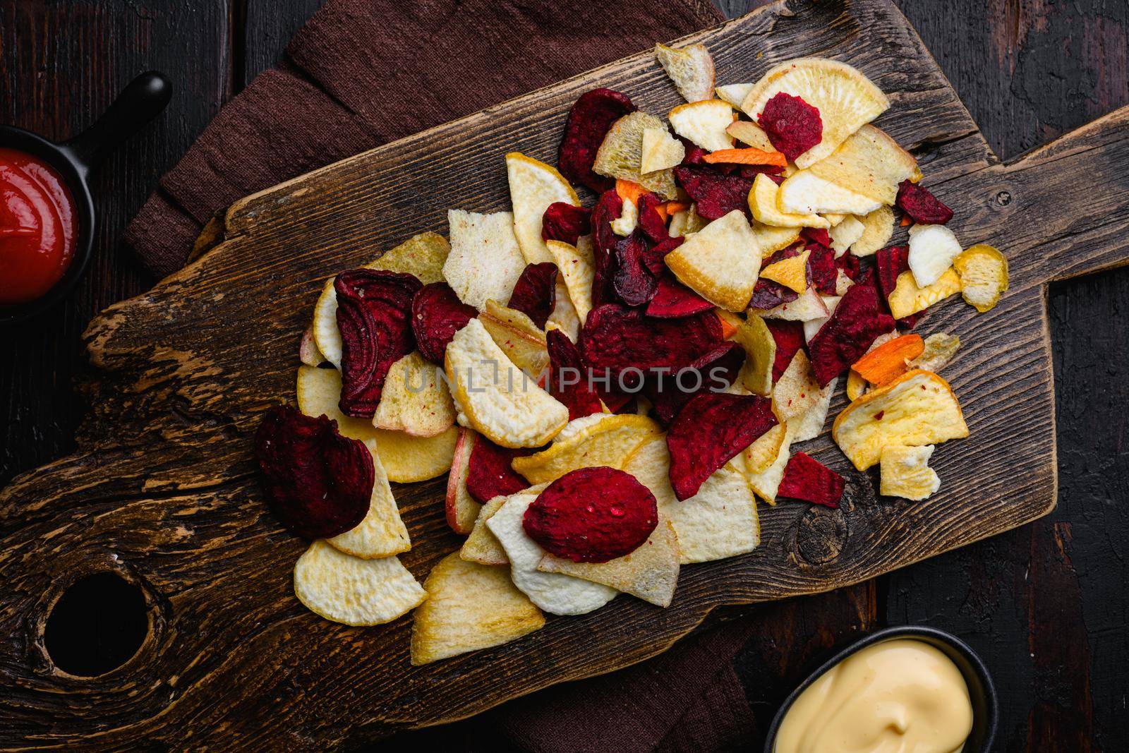 Dried vegetables chips, on black wooden table background, top view flat lay by Ilianesolenyi