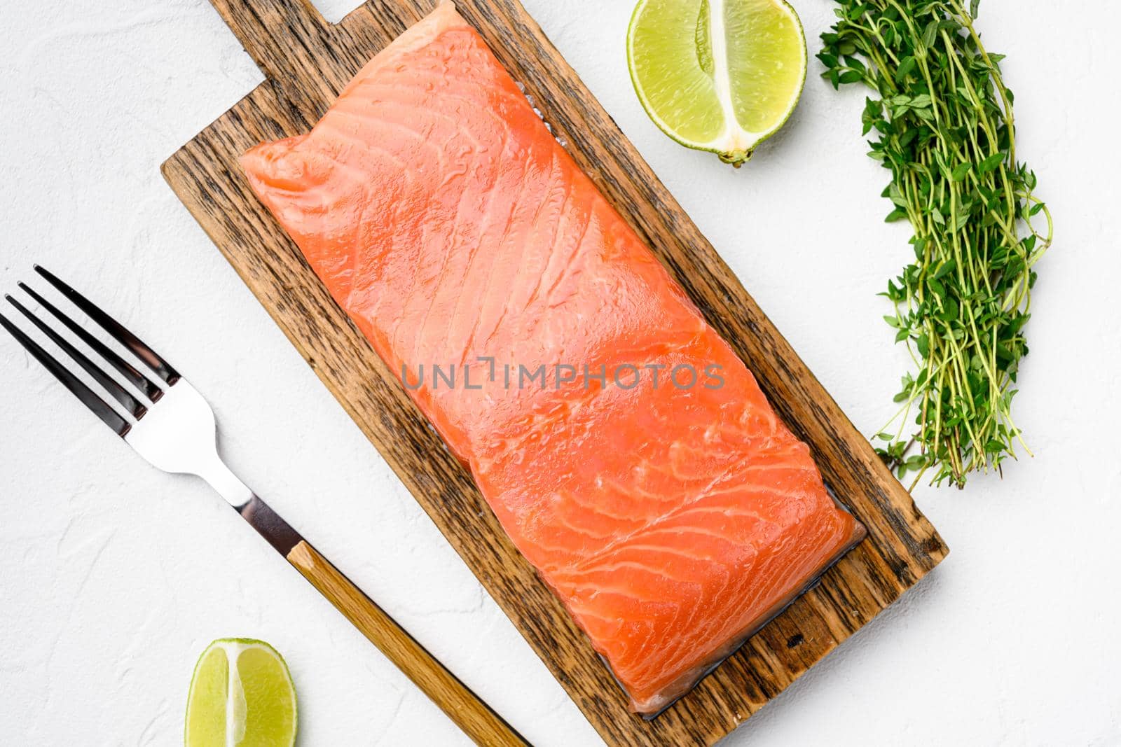 Portioned raw salmon fillet set, with herbs, on white stone table background, top view flat lay