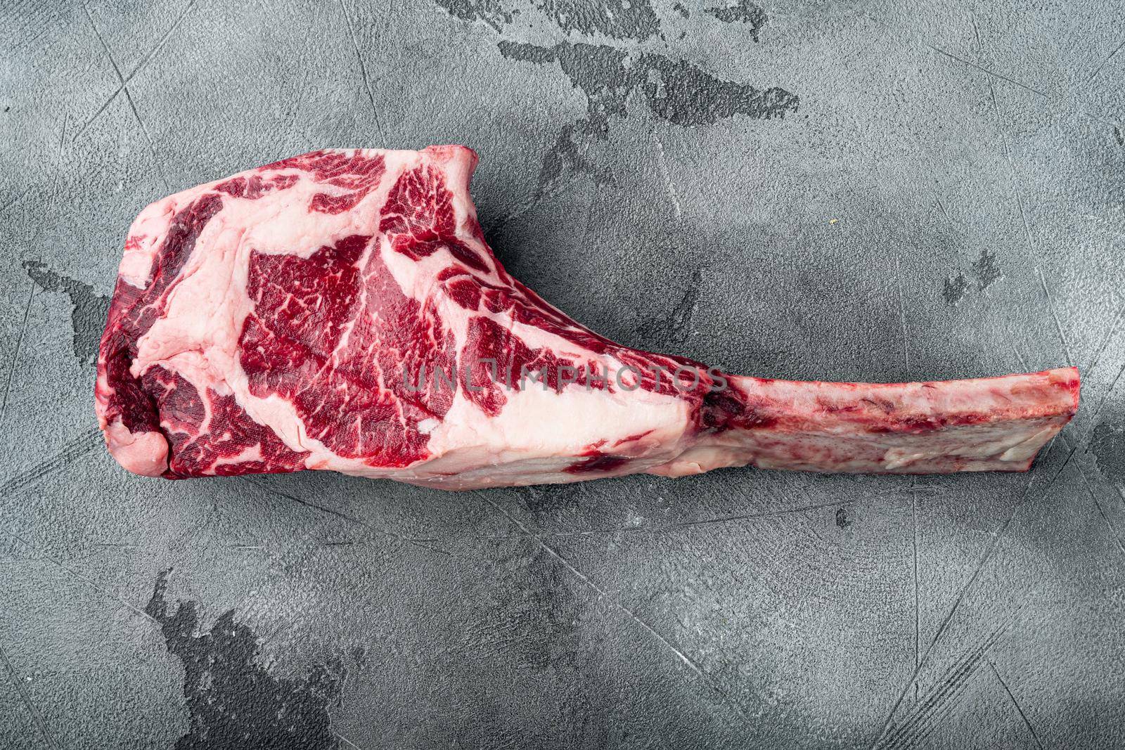 Raw fresh tomahawk black angus prime beef chop steak set, on gray stone background, top view flat lay, with copy space for text