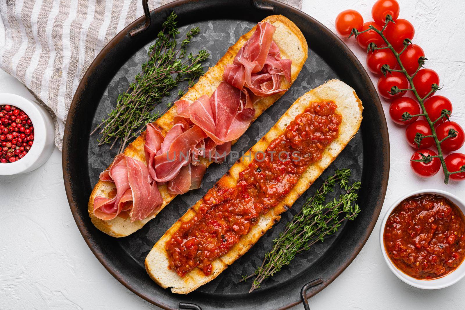 Crusty toast with fresh tomatoes and cured ham set, on white stone table background, top view flat lay by Ilianesolenyi