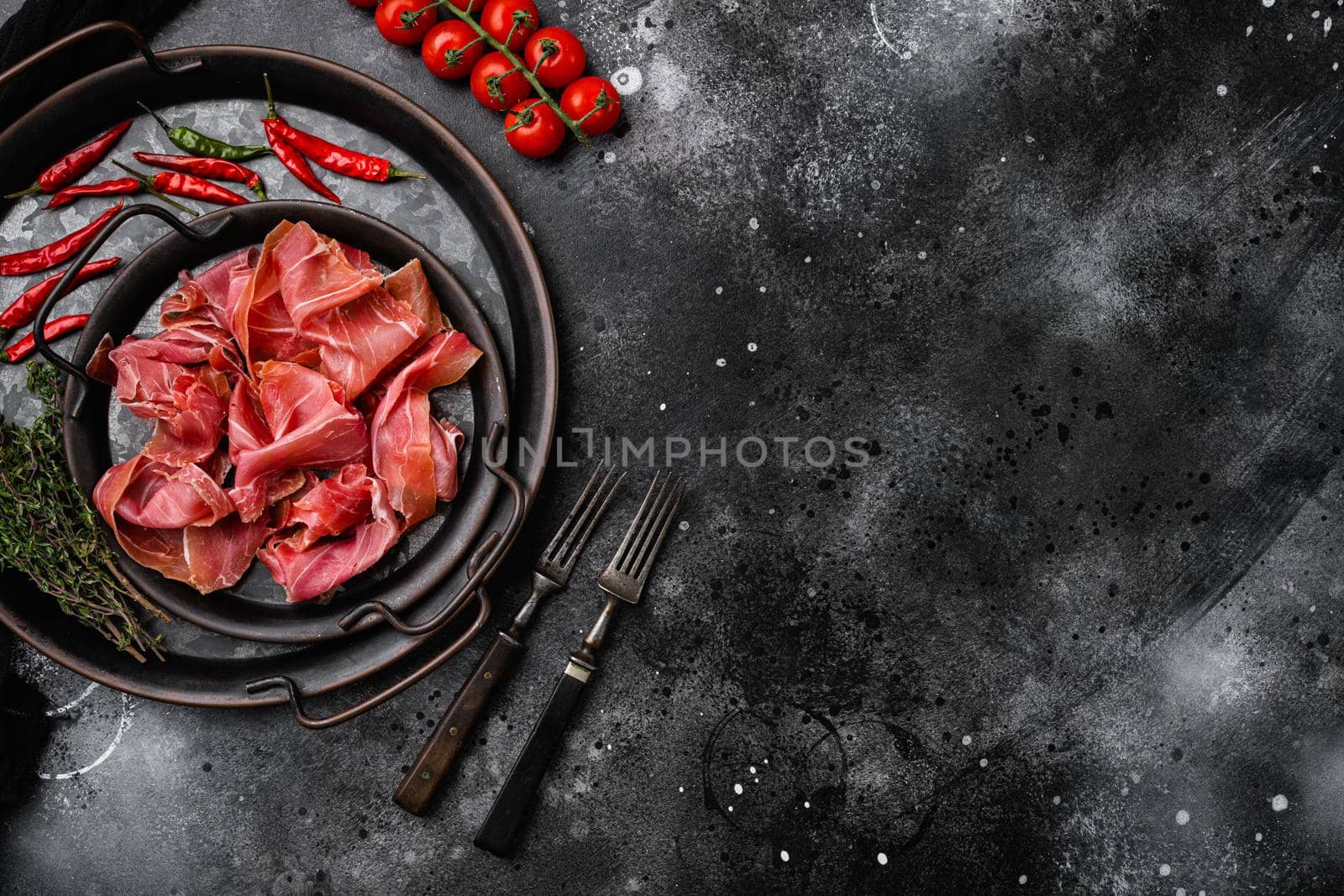 Italian prosciutto crudo or spanish jamon set, on black dark stone table background, top view flat lay, with copy space for text by Ilianesolenyi