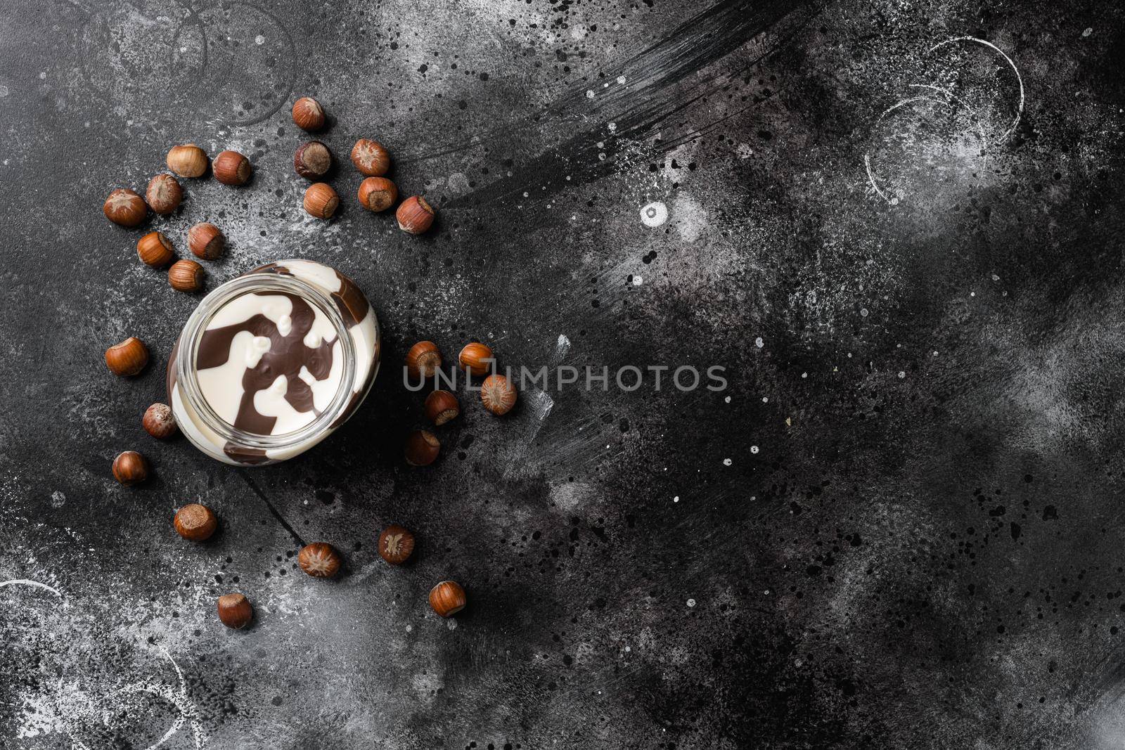 Chocolate hazelnut in jar with nuts, on black dark stone table background, top view flat lay, with copy space for text by Ilianesolenyi