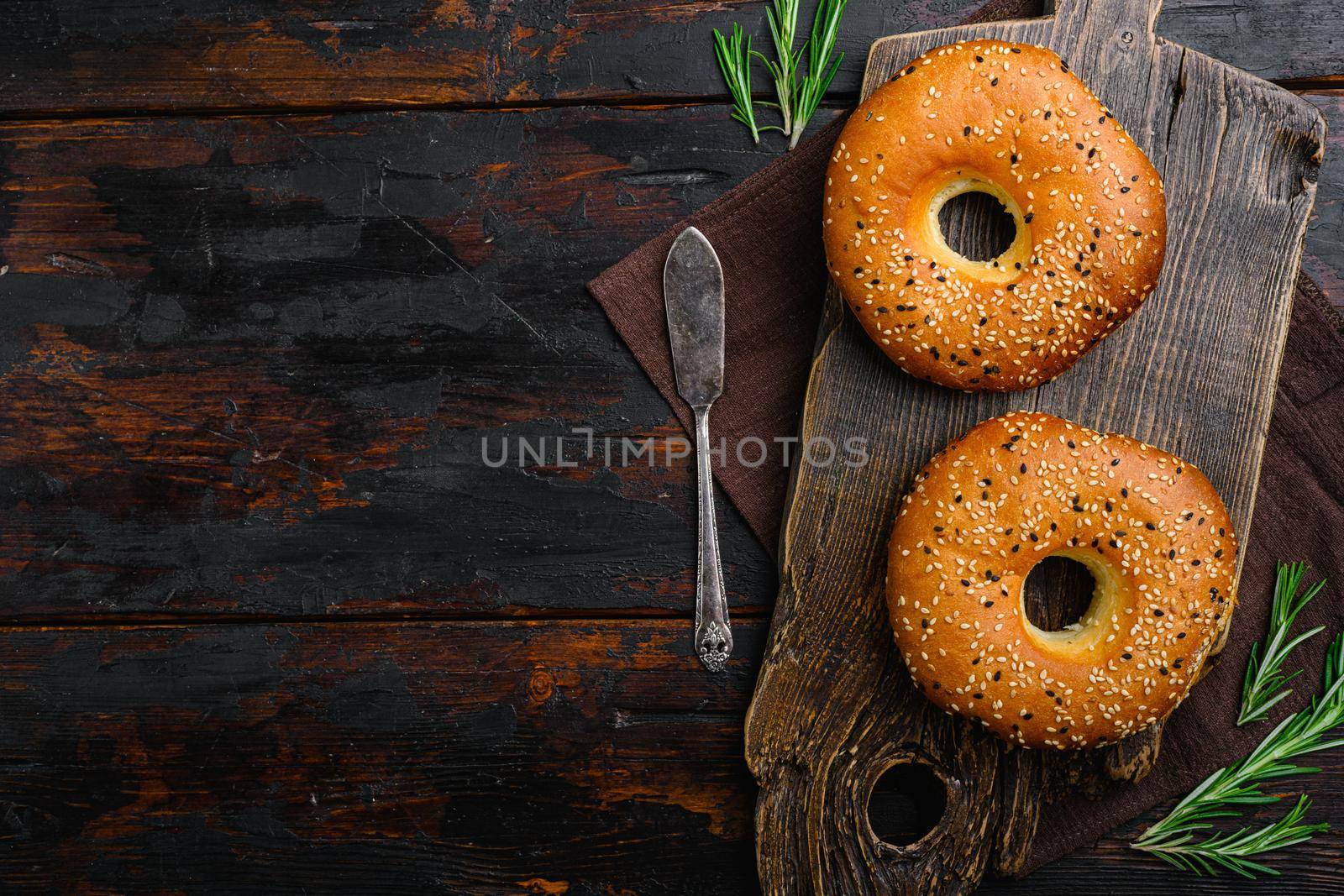 Fresh Sesame Bagel, on old dark wooden table background, top view flat lay, with copy space for text