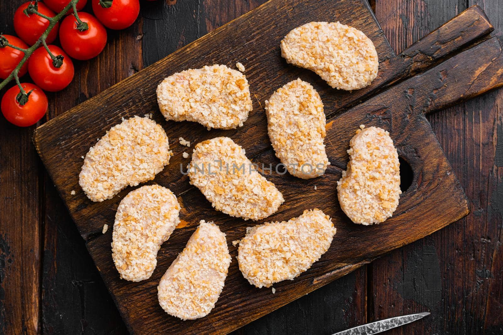Homemade Raw Breaded Chicken Nuggets set, on old dark wooden table background, top view flat lay by Ilianesolenyi