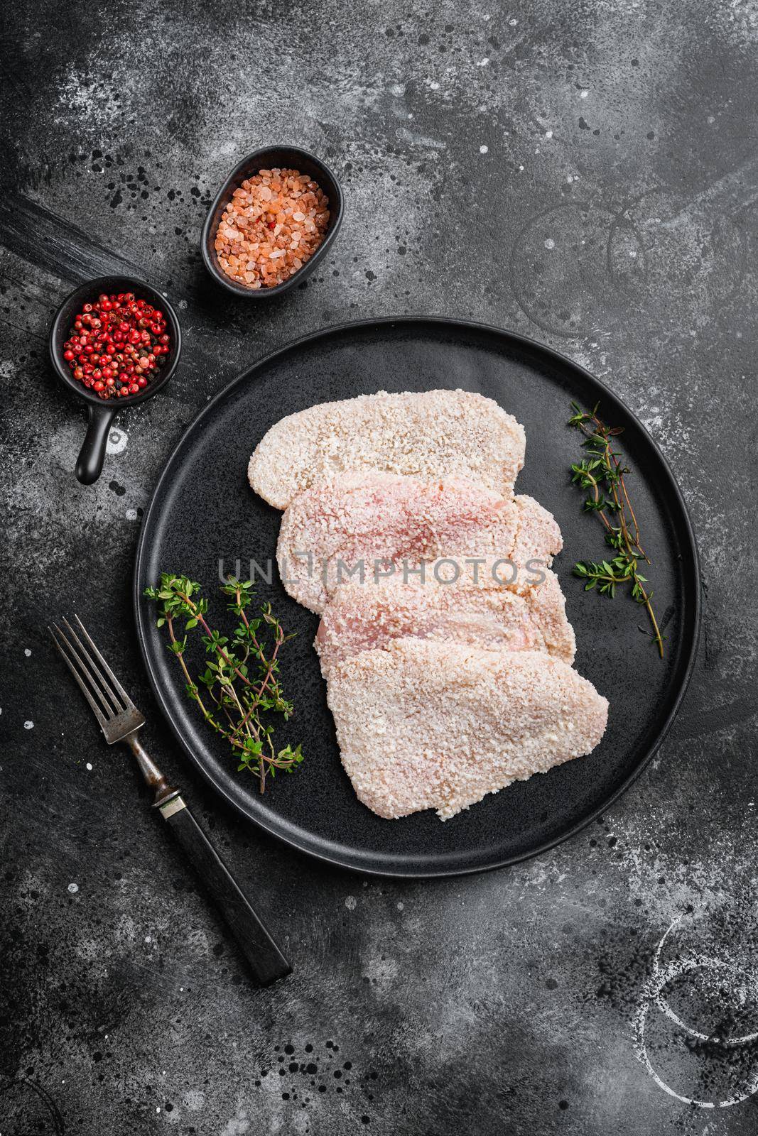 Raw schnitzel chicken meat set, on black dark stone table background, top view flat lay, with copy space for text by Ilianesolenyi