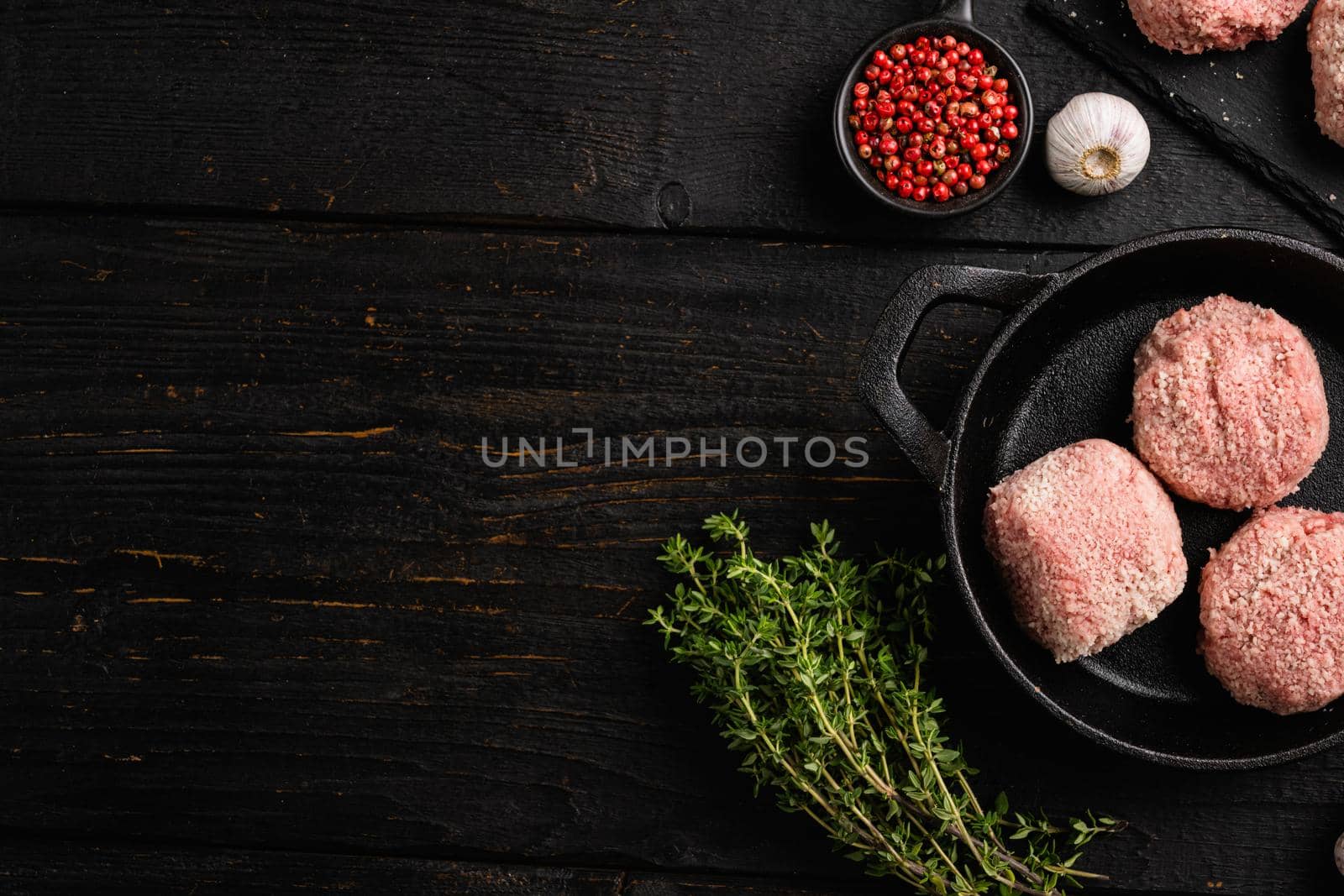 Raw chicken cutlets, ground meat patty, on black wooden table background, top view flat lay, with copy space for text by Ilianesolenyi