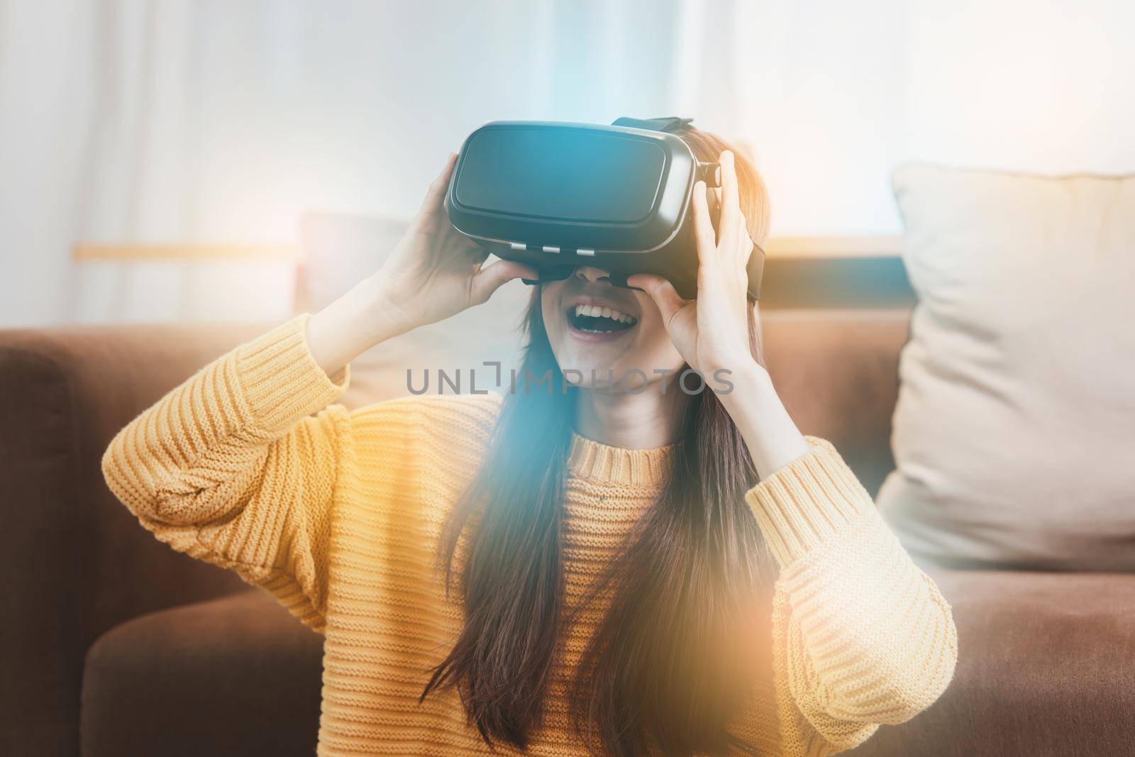 Exciting asian woman with wearable VR headset playing sport gaming online in living room at home