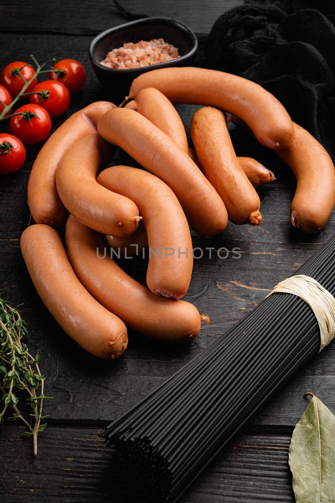 Raw sausage, on black wooden table background by Ilianesolenyi