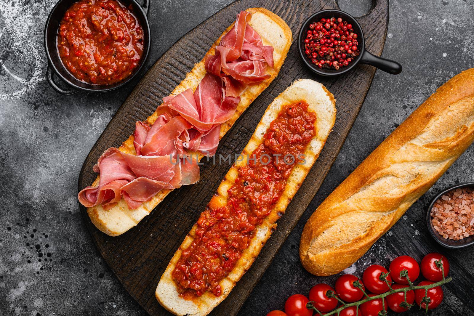 Spanish cured serrano ham with olive oil and toasted bread set, on black dark stone table background, top view flat lay