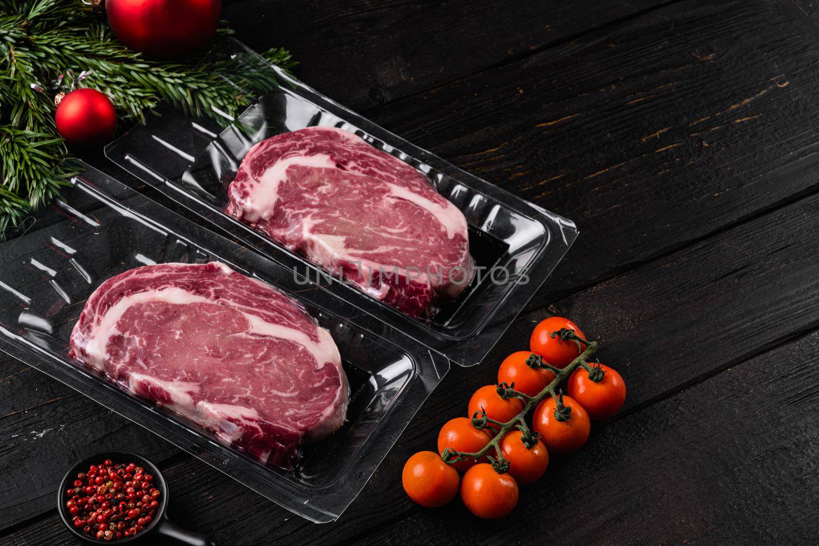 Meat in a package, on black wooden table background, with copy space for text by Ilianesolenyi