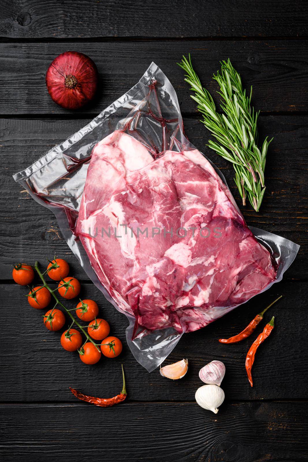 Raw chopped lamb fillet pack, with ingredients and herbs, on black wooden table background, top view flat lay by Ilianesolenyi