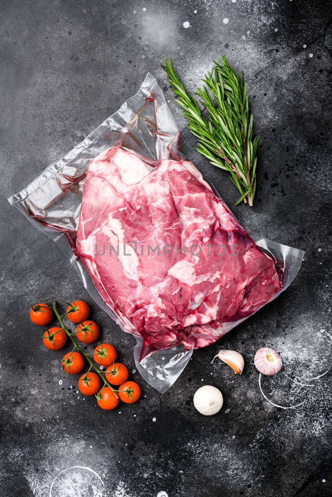 Fresh raw mutton shoulder meat, with ingredients and herbs, on black dark stone table background, top view flat lay by Ilianesolenyi