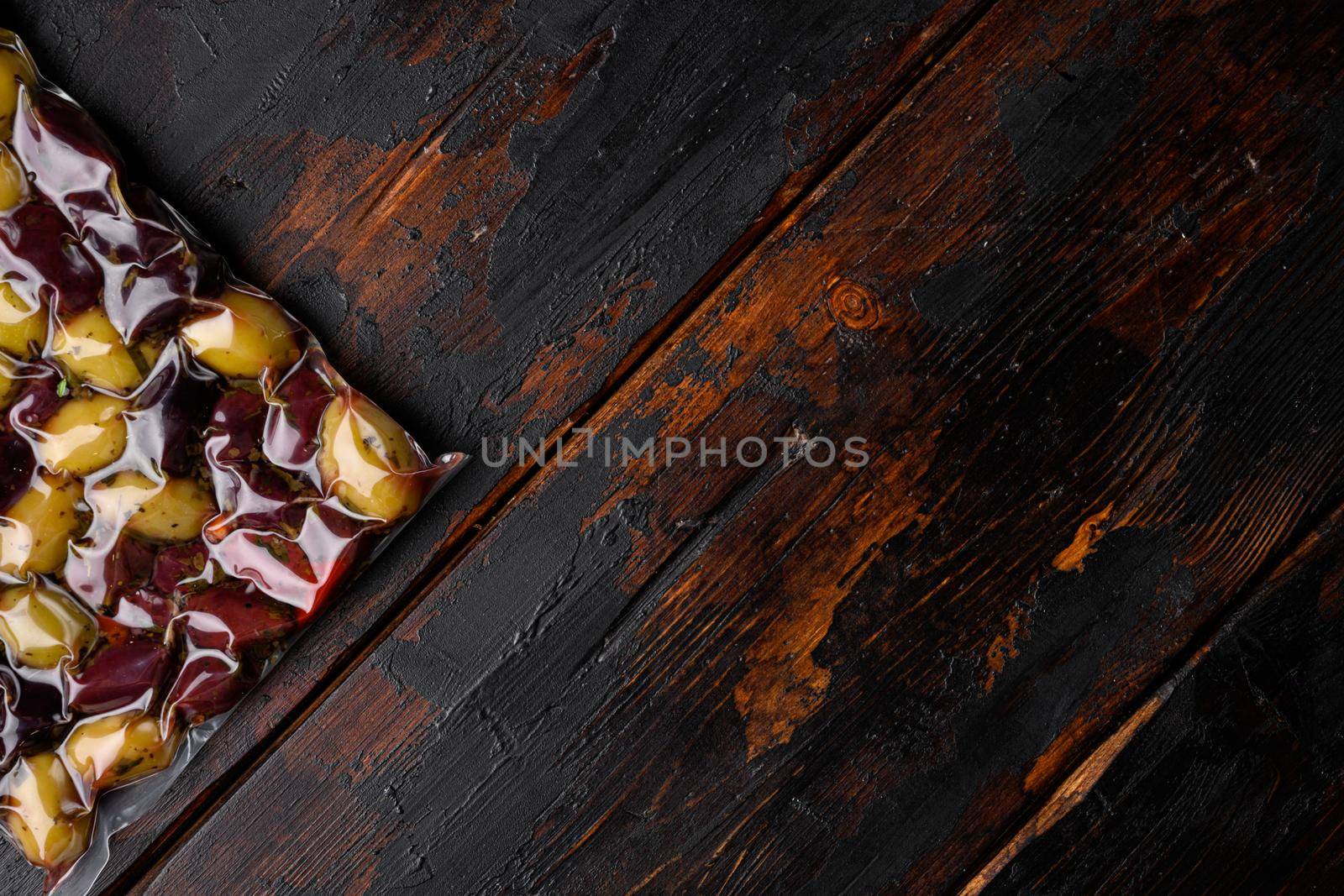 Olives in vacuum pack no label set, on old dark wooden table background, top view flat lay, with copy space for text