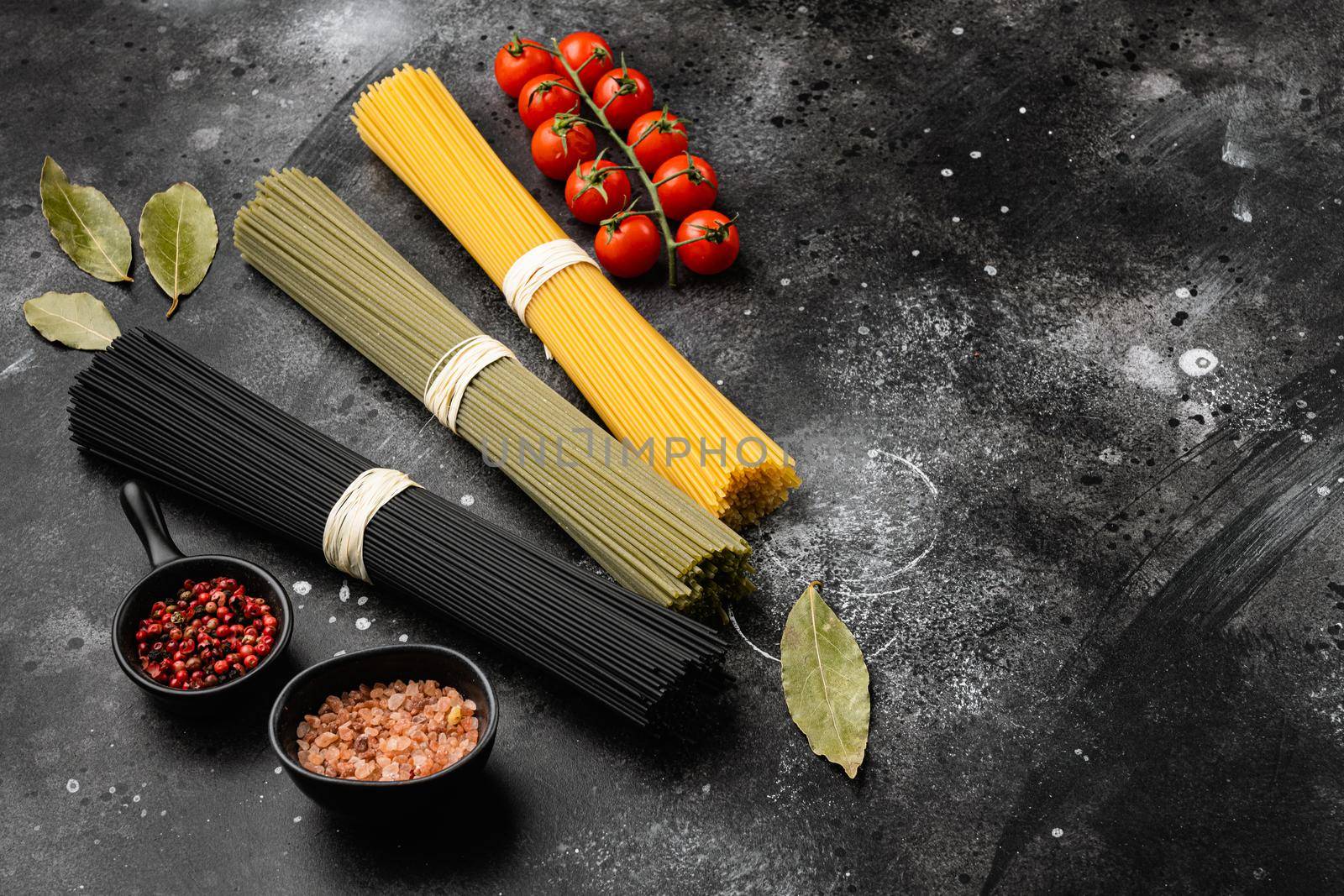 Colored dry italian pasta, on black dark stone table background, with copy space for text by Ilianesolenyi