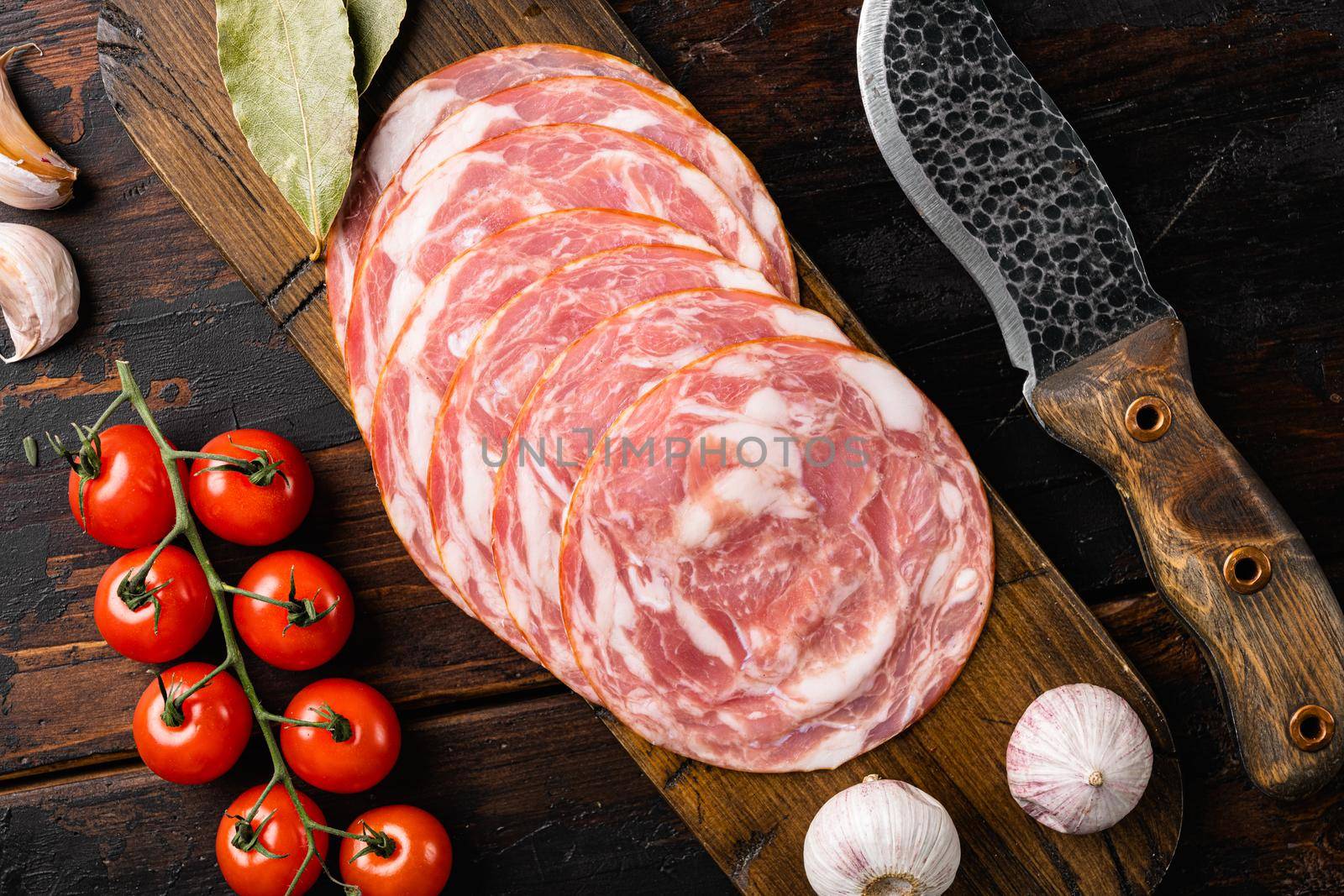 Sliced raw smoked sausage, on old dark wooden table background, top view flat lay by Ilianesolenyi