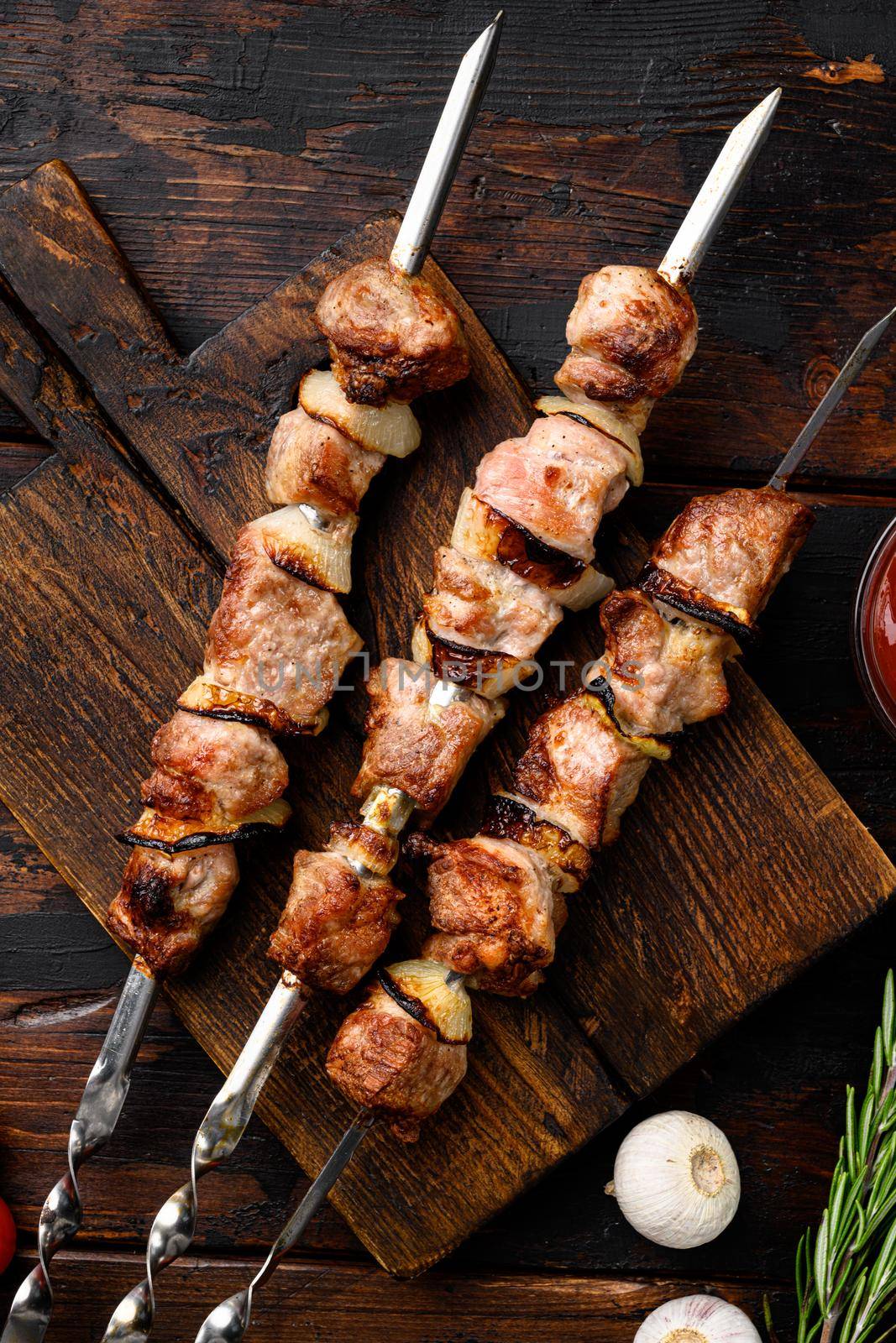 Shish kebab BBQ meat with onions and tomatoes, on old dark wooden table background, top view flat lay by Ilianesolenyi