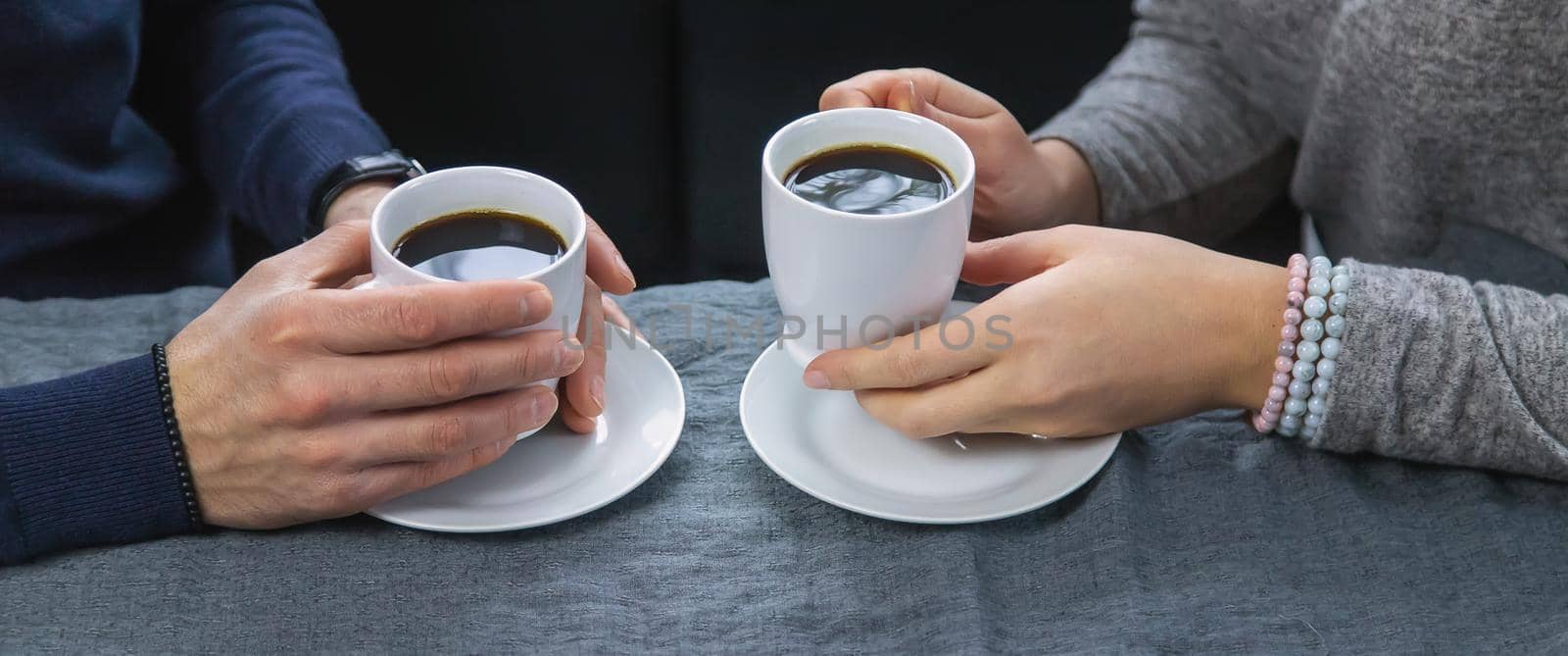 Man and woman at the table with a cup of coffee. Selective focus. by yanadjana