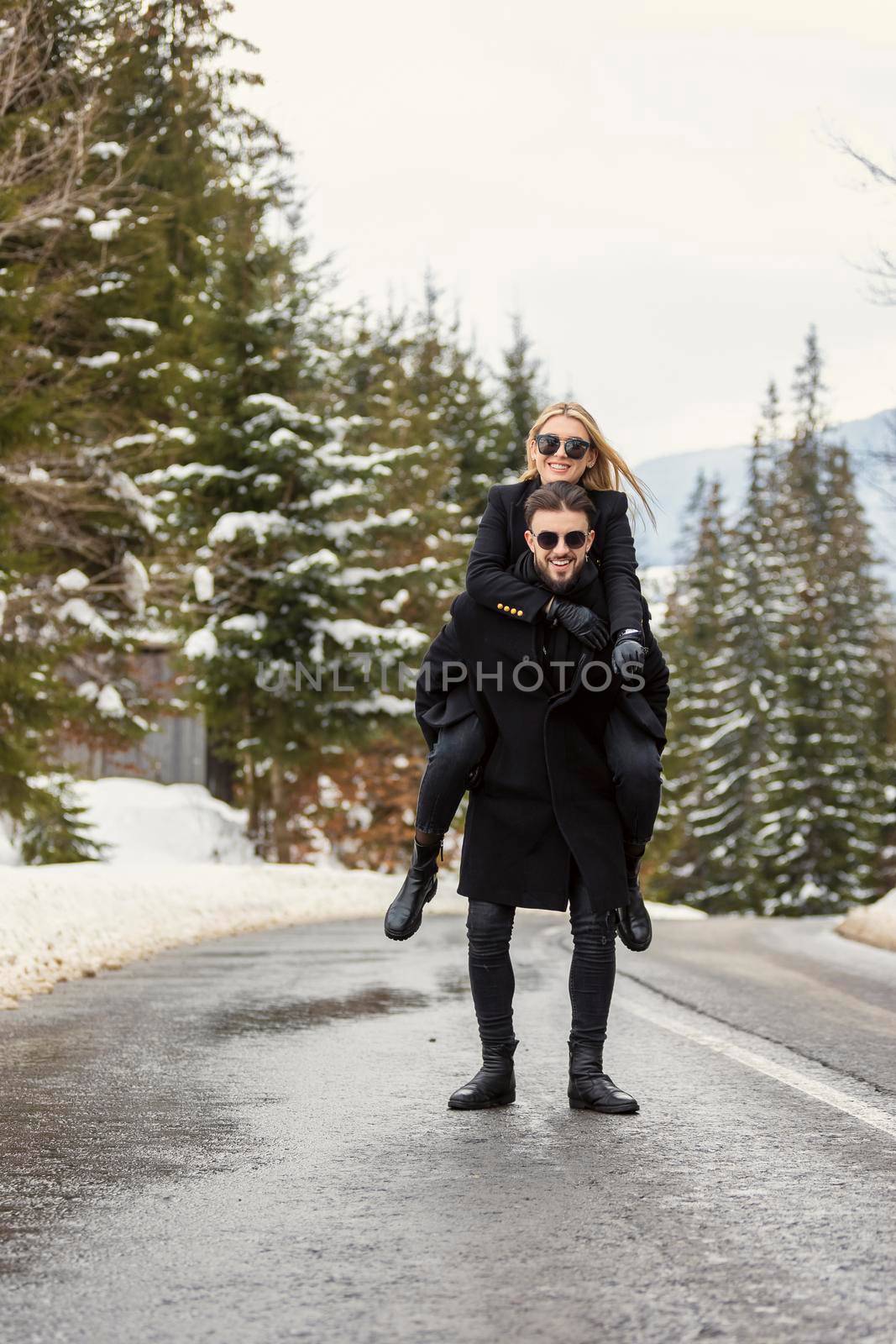 a guy with a girl on his back are walking on the road