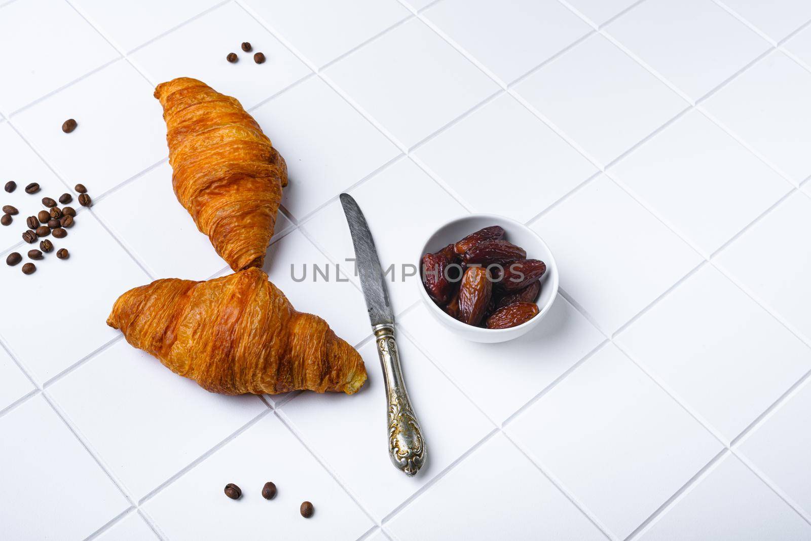 Fresh croissants on table set, on white ceramic squared tile table background, with copy space for text by Ilianesolenyi