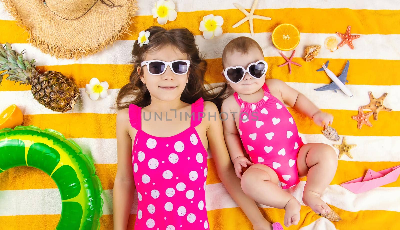 Baby sisters on a beach towel at the sea. Selective focus. Child.