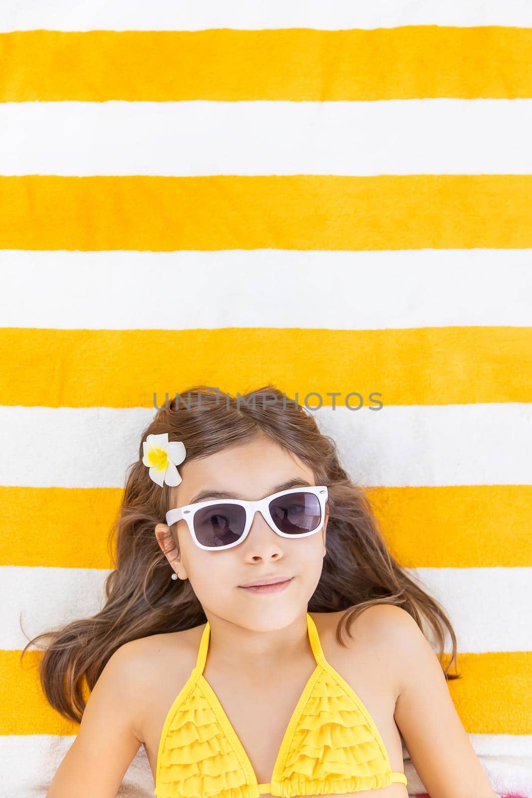 Child girl on a beach towel by the sea. Selective focus. by yanadjana