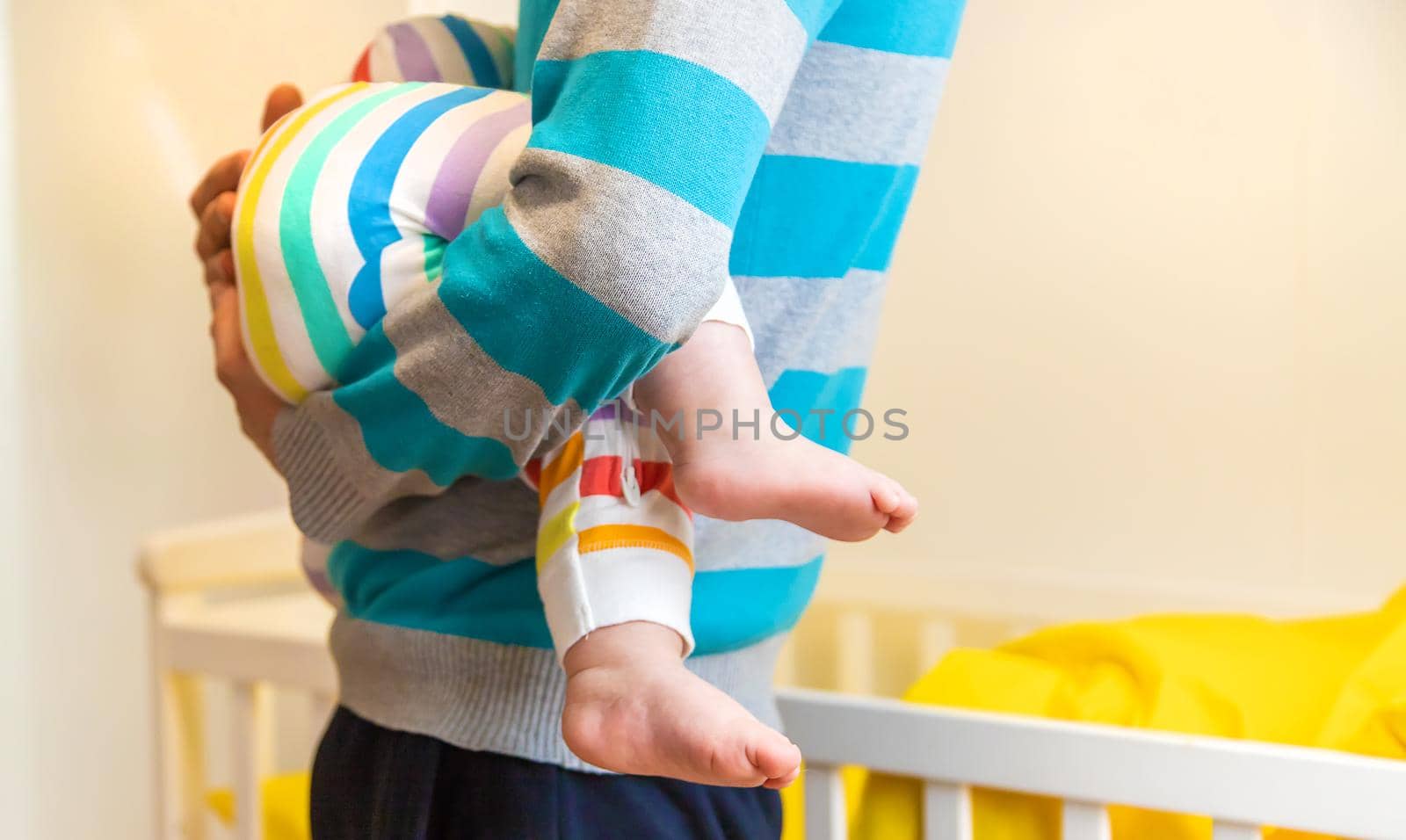 The father puts the baby to sleep in his arms. Selective focus. People.