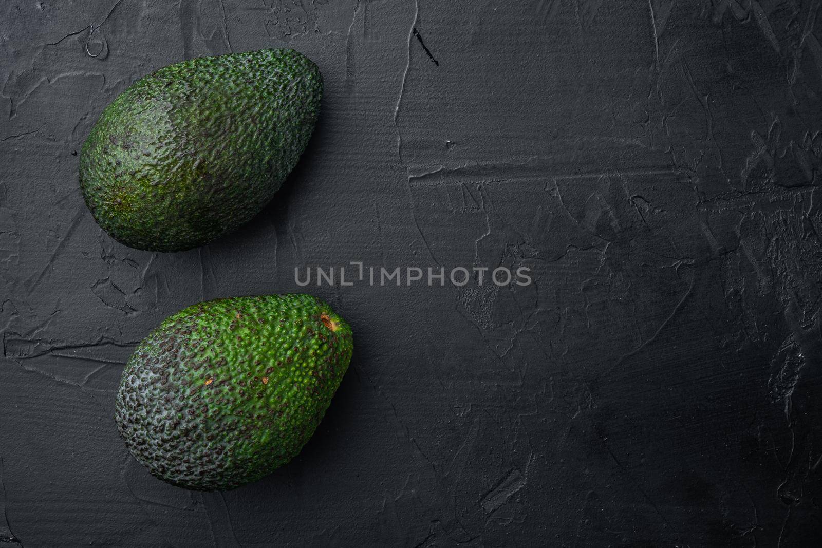 Ripe pair of green avocado, on black background, top view or flat lay with copy space for text by Ilianesolenyi