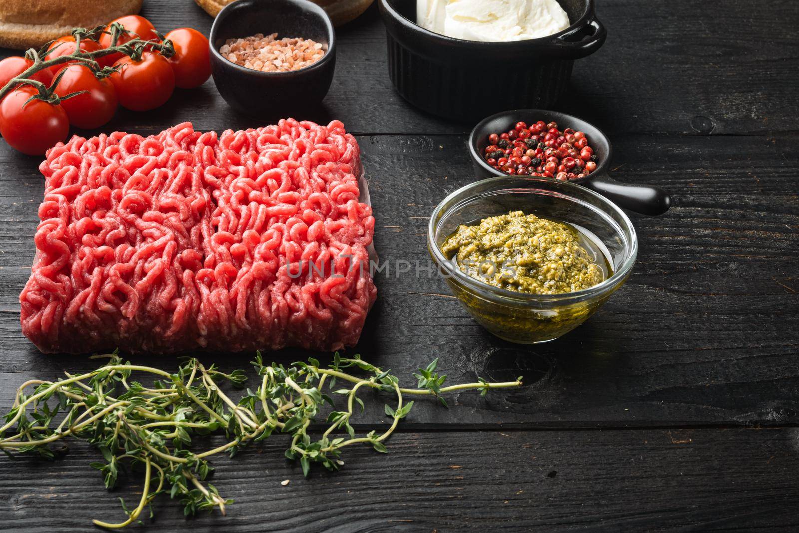 Raw meatballs made from ground beef ingredients, on black wooden table background by Ilianesolenyi