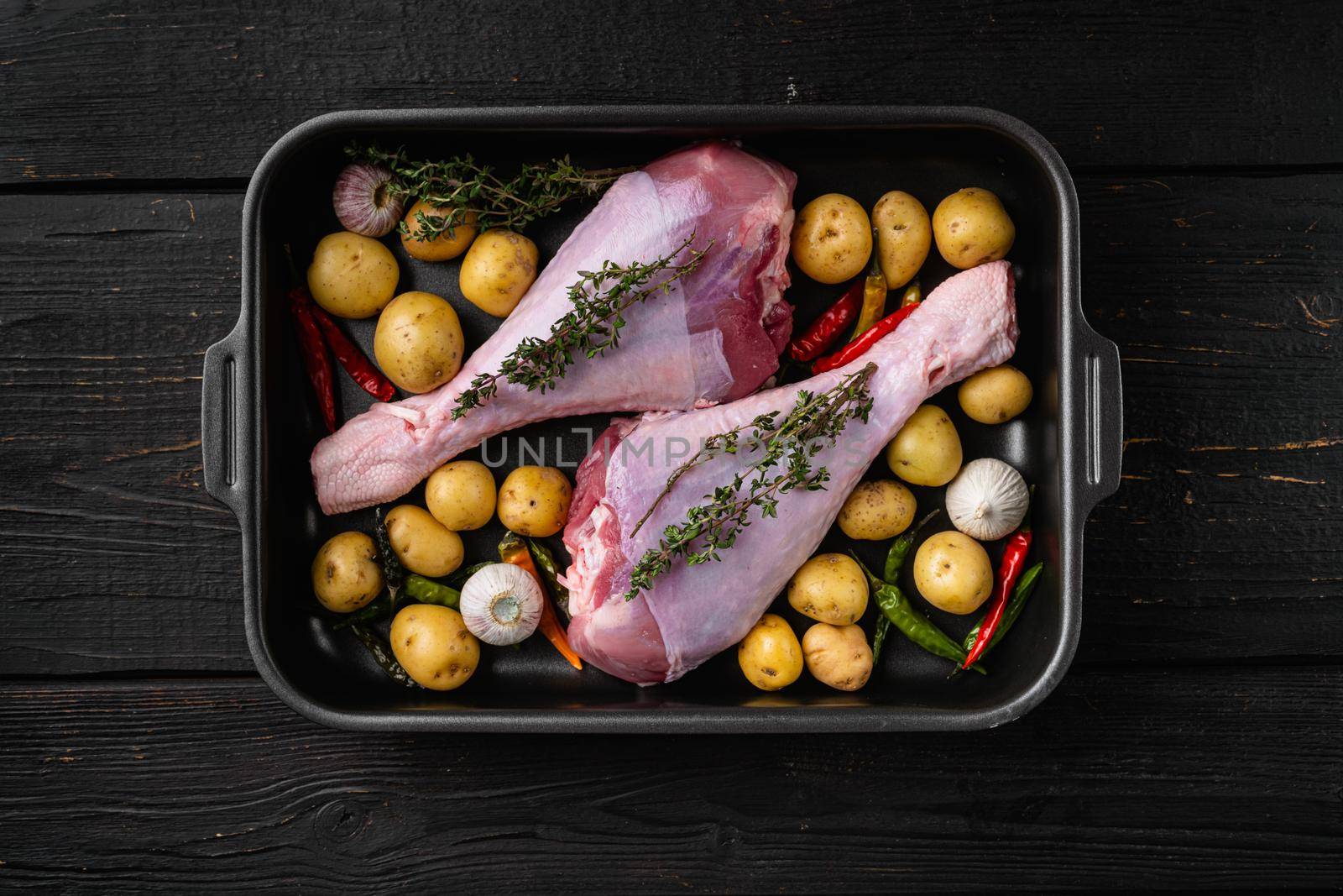 Raw turkey drumsticks with thyme, pepper, on black wooden table background, top view flat lay, with copy space for text by Ilianesolenyi