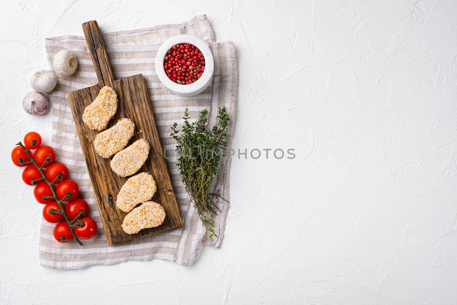 Homemade Raw Breaded Chicken Nuggets set, on white stone table background, top view flat lay, with copy space for text by Ilianesolenyi