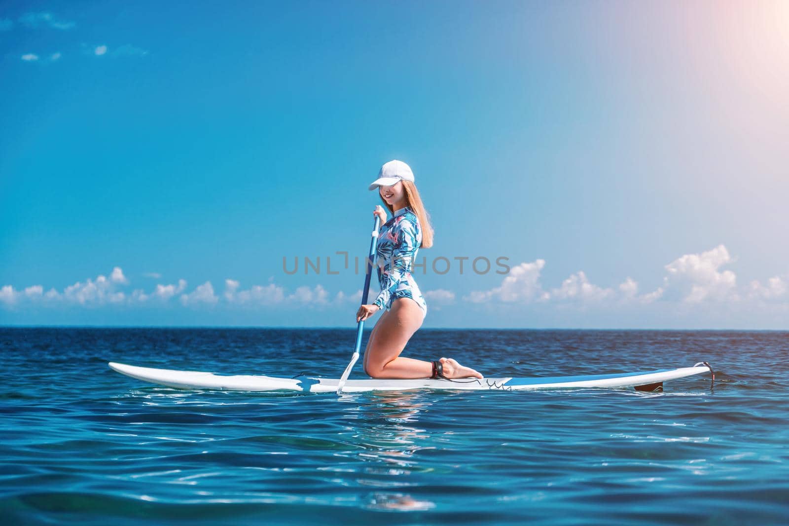 Healthy happy fit woman in bikini relaxing on a sup surfboard, floating on the clear turquoise sea water. Recreational Sports. Stand Up Paddle boarding. Summer fun, holidays travel. Active lifestyle by panophotograph