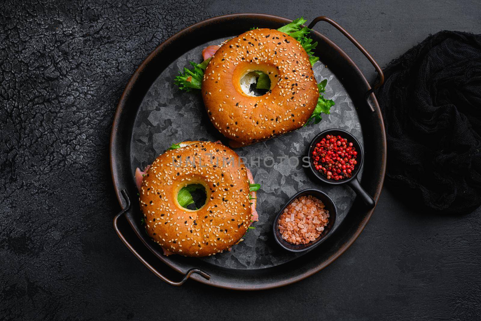 Bagel sandwich with salmon set, on black dark stone table background, top view flat lay