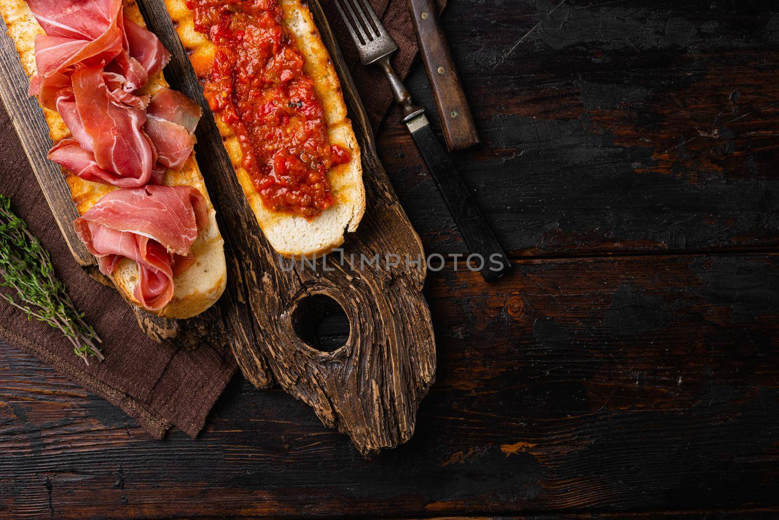 Spanish cured serrano ham with olive oil and toasted bread set, on old dark wooden table background, top view flat lay, with copy space for text