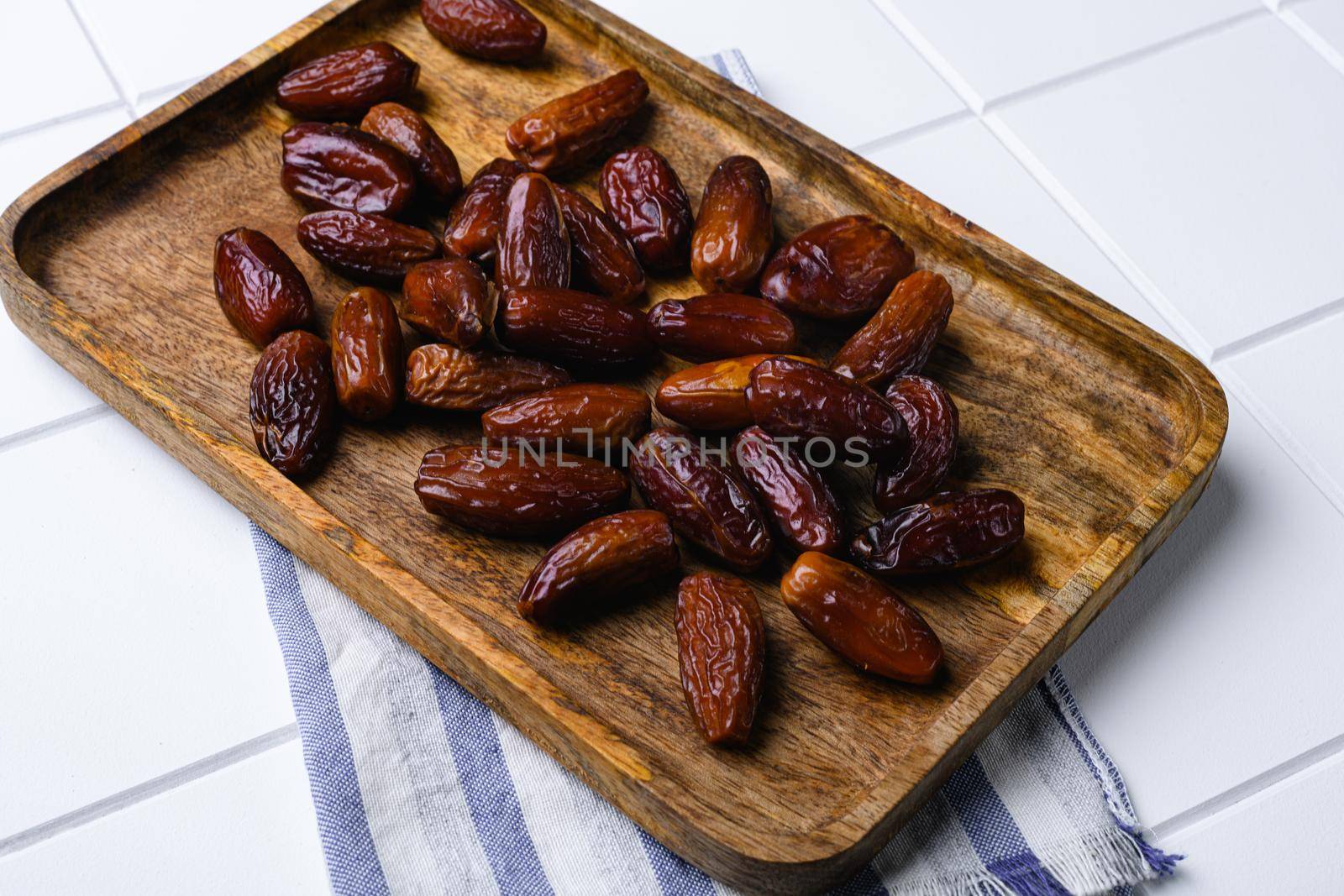 Traditional arabic dry dates set, on white ceramic squared tile table background by Ilianesolenyi