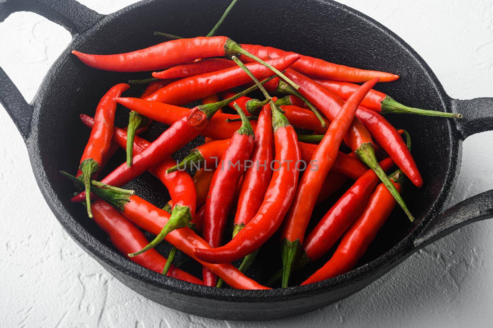 Hot Red thai pepper set, in frying cast iron pan, on white stone background