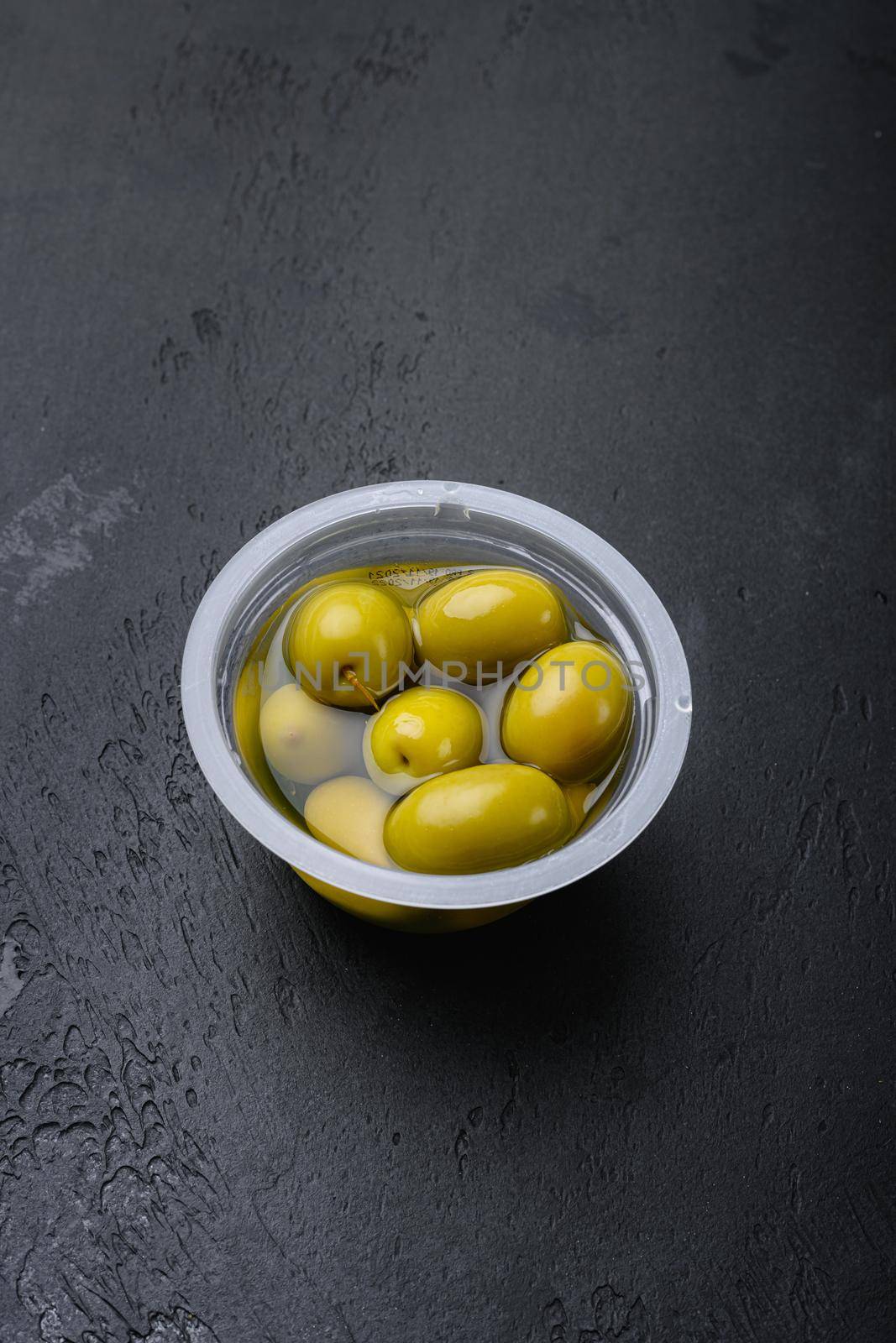 Green olives in oil set, on black dark stone table background, with copy space for text by Ilianesolenyi