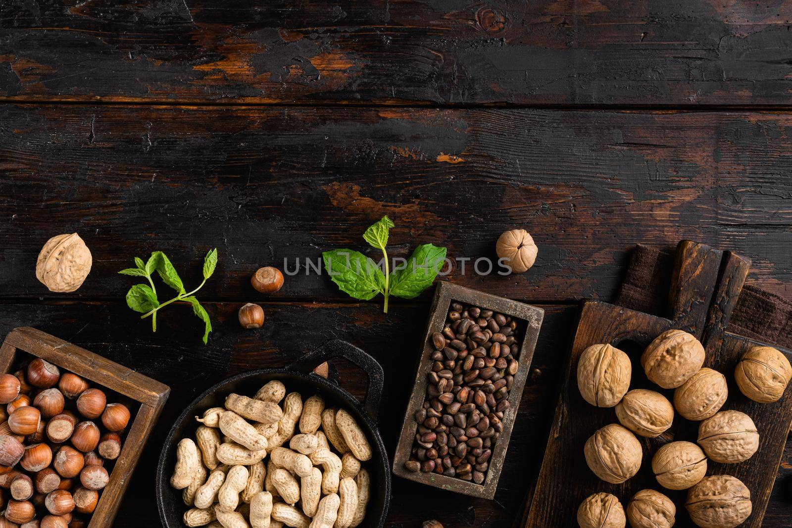 Assortment of nuts in shells, peanut, walnut, pine nuts and hazelnut set, on old dark wooden table background, top view flat lay, with copy space for text