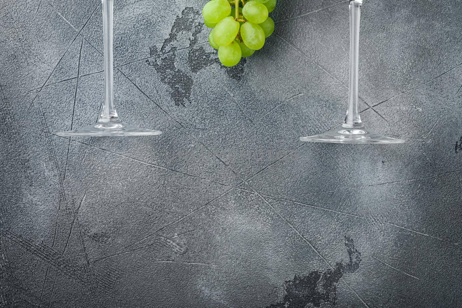 Wineglasses with grapes, on gray stone background, top view flat lay, with copy space for text by Ilianesolenyi