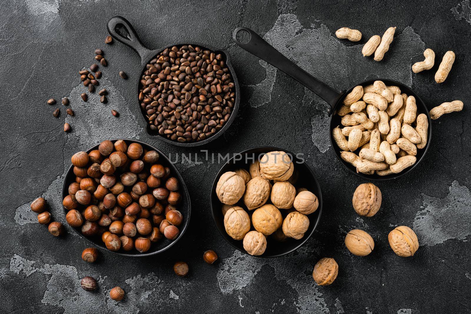 Nuts mix, peanut, walnut, pine nuts and hazelnut set, on black dark stone table background, top view flat lay