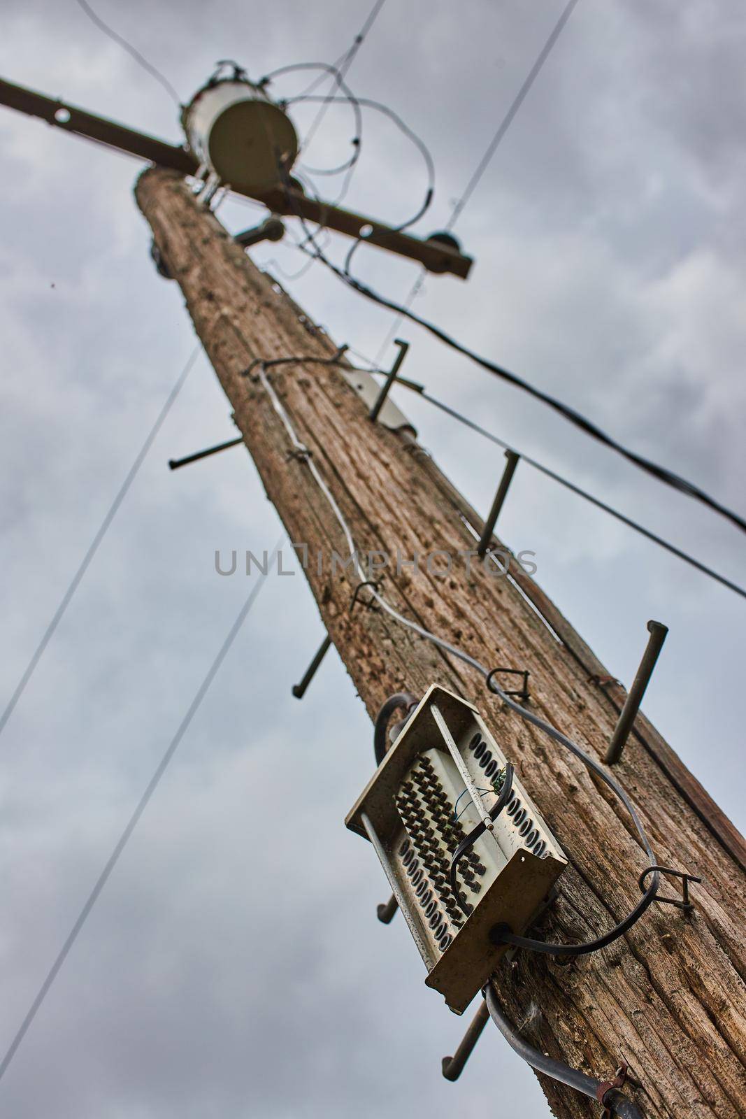 Telephone pole looking up detail on cloudy day for communication and power by njproductions