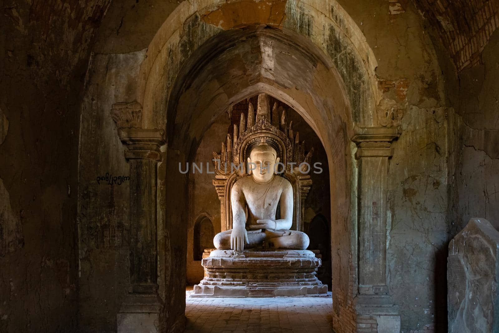 A statue of Buddha stands in the middle of a large stupa in the sacred cultural landscape of Bagan