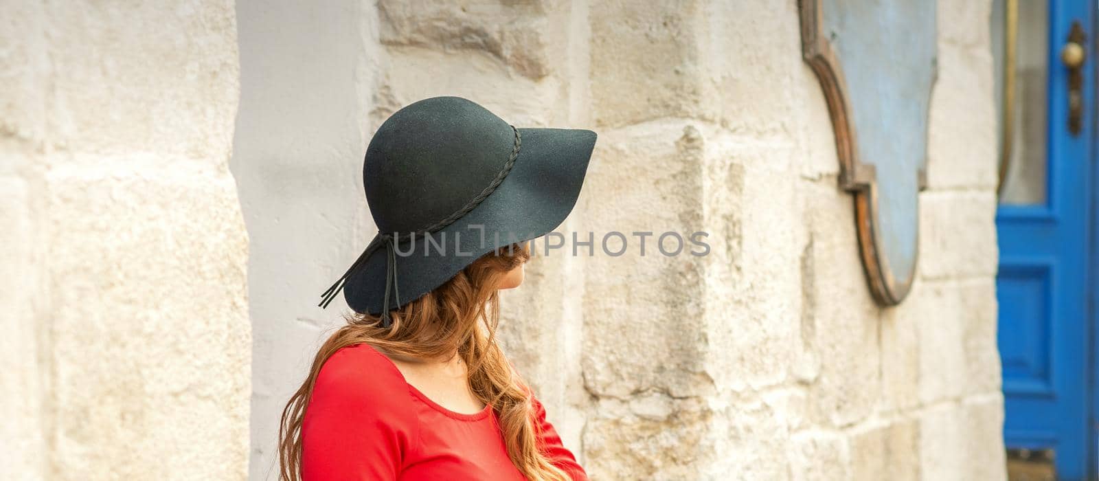 Beautiful young caucasian woman wearing black hat and red dress