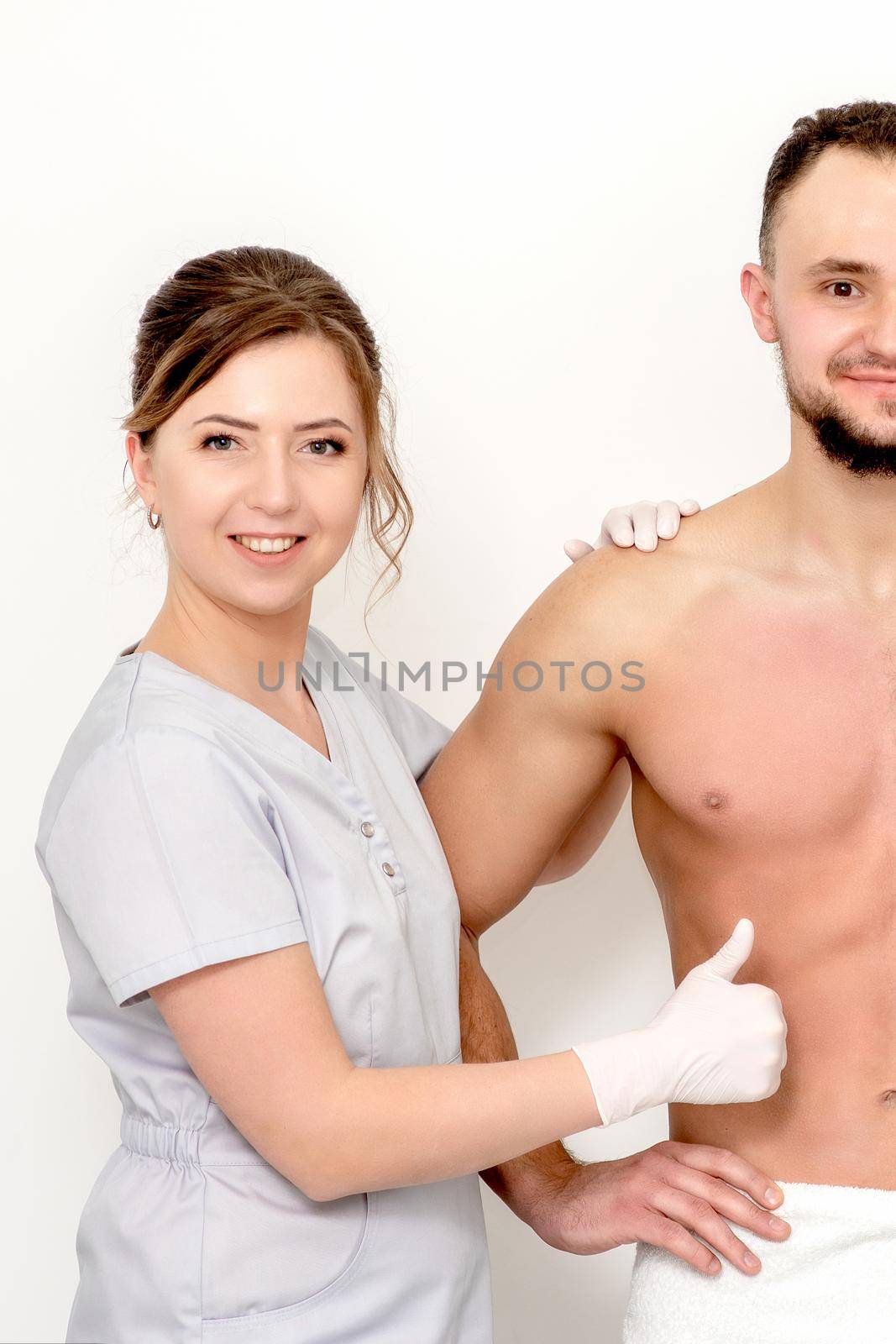 Young caucasian man with bare chested before and after waxing his hair with thumb up of hand of beautician standing on white background