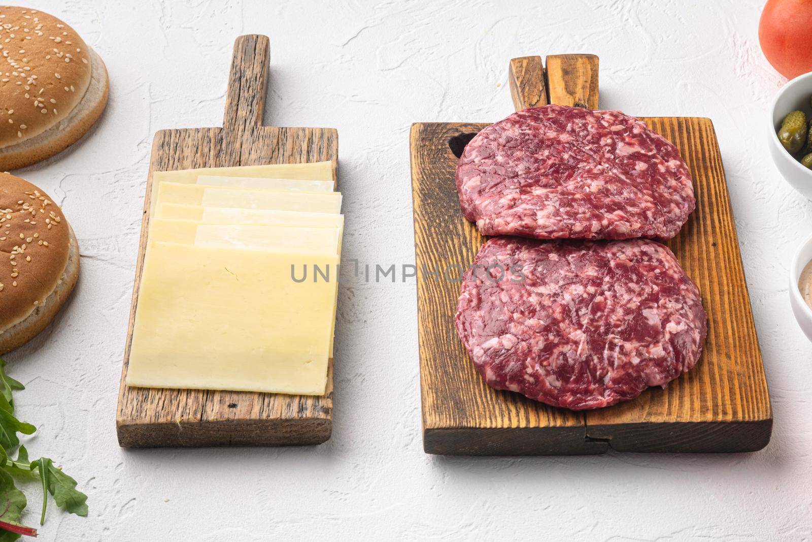 Ingredients for cooking burgers. Raw ground beef meat cutlets, on white stone background by Ilianesolenyi