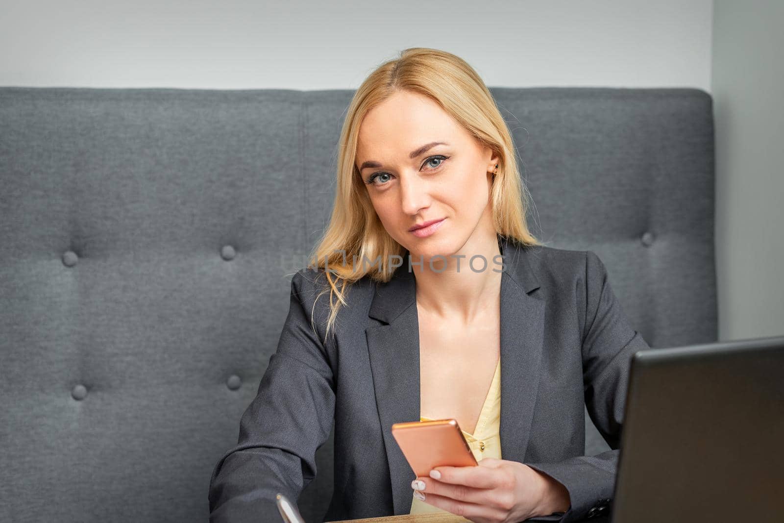 Portrait of beautiful young caucasian businesswoman with smartphone working in office looking at camera