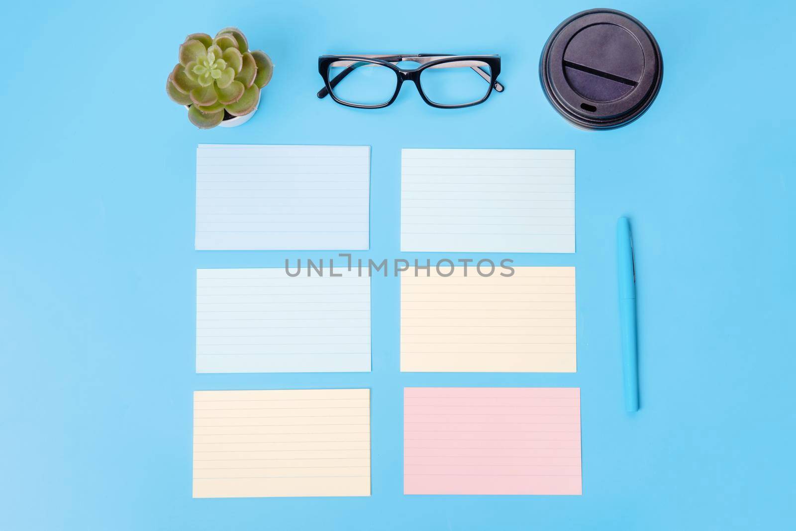 blank, notepaper, piece of paper, coffee, glasses, plant and pen on blue background. workplace. Space for text. The financial checks
