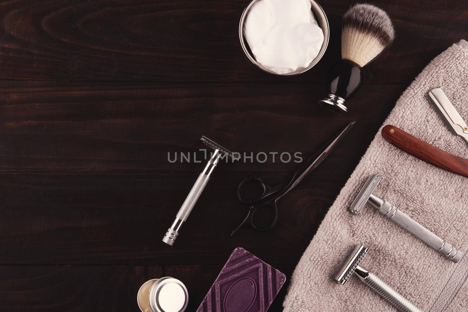 vintage razors, shaving brush, soap and foam in a bowl on a dark wooden background. View above. Space for text