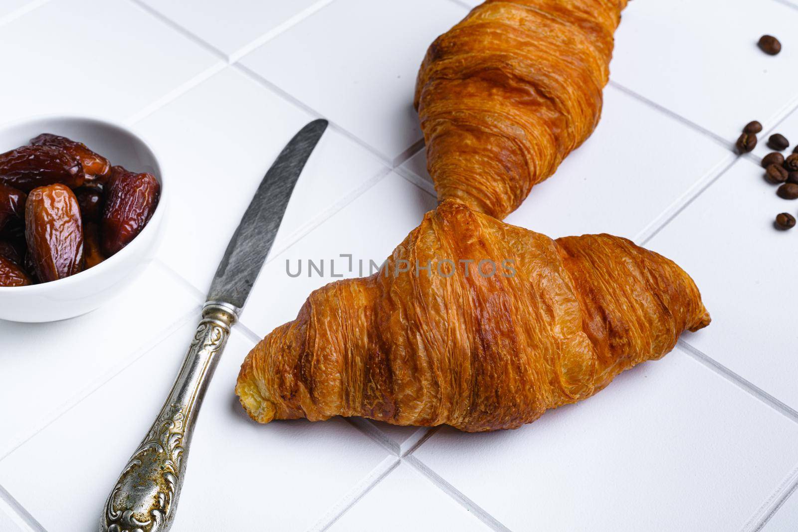 Warm butter creamy baked croissants set, on white ceramic squared tile table background by Ilianesolenyi
